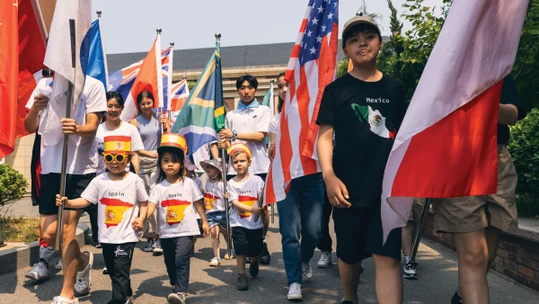 烟台华盛国际学校幼儿中心的同学们带着大龄同学和旗子走在一起