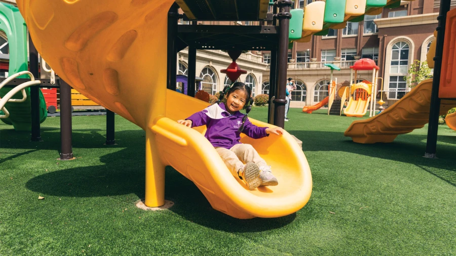 young smiling female student at yantai huasheng international school admissions including an outdoor playground