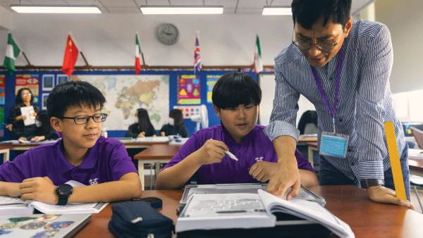 male teacher helping two yantai huasheng international school middle school male students