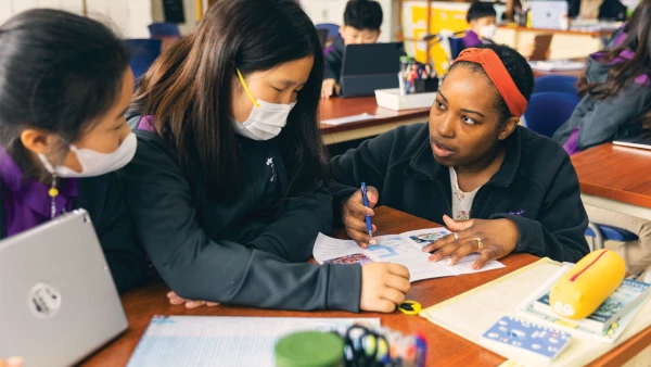 teacher helping young female students inside classroom at yantai huasheng international school