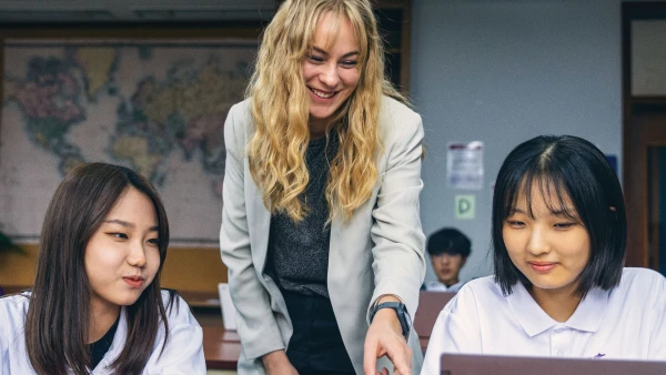 two female students in yantai huasheng international school learning from their teacher