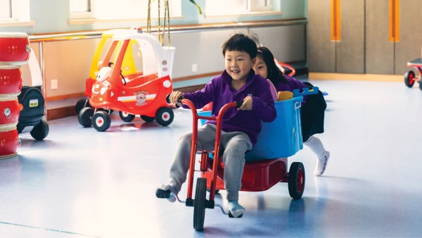 male and female student playing on tricycle in yantai huasheng international school early childhood center play room